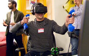 Young man holds reactive grip hand devices while wearing virtual reality goggles