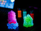 Three fluorescently glowing objects with complex lattice structures on a dark background.