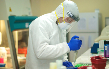 A researcher in protective gear works in a lab.