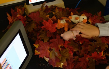 stuffed animals sitting on leaves next to a monitor