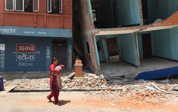 woman walking on a street with damaged buildings after the quake.