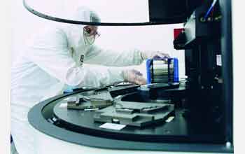 A technician at Texas Instruments processes wafers containing computer microchips