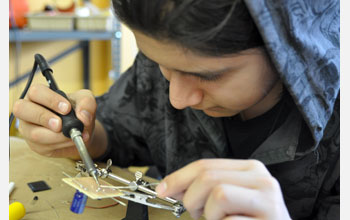 GreenFab student participant solders together a solar-powered robot