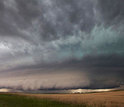 Photo of sky and a large wall cloud arcs around a rotating thunderstorm updraft in Nebraska.