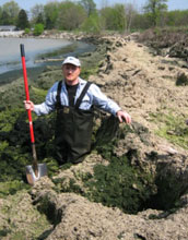 Researcher With shovel knee deep in an algae accumulation along Lake Erie