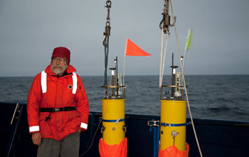 Photo of scientist Eric D'Asaro standing on deck with robotic floats he developed.