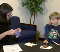 a researcher on the left holding an image and a young boy looking at the image.