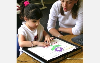 A kindergartner examines a Talking Tactile Tablet picture of a flower.