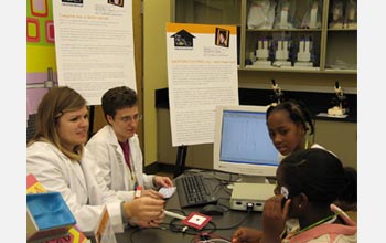 Photo of graduate students assisting a visitor in applying electrodes measuring eye movements.