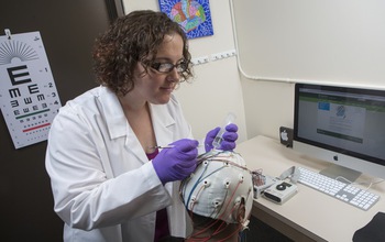 Sarah Laszlo prepares a subject to measure brain activity using electroencephalography (EEG).