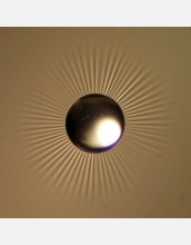 A starburst of wrinkles form in a thin film material when a drop of water is placed on the film.