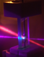 Two laser beams cross in a glass cuvette that holds a transparent liquid