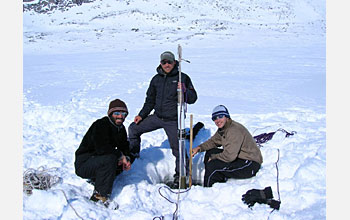 Photo showing three people and a lake sediment core.