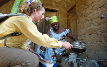Scientist showing local Ghanian woman how to use a new cookstove.