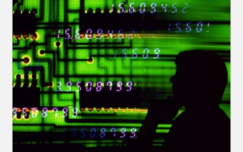 Representation of computer technology, with a circuit board and the silhouette of a computer user.