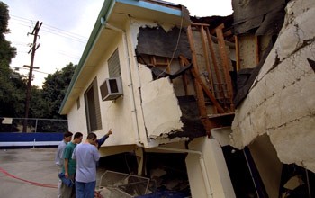 several people and an earthquake-damaged house
