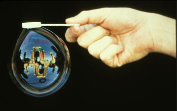 a hand generating a bubble containing an image of the Exploratorium.