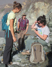 students in field analyzing rocks