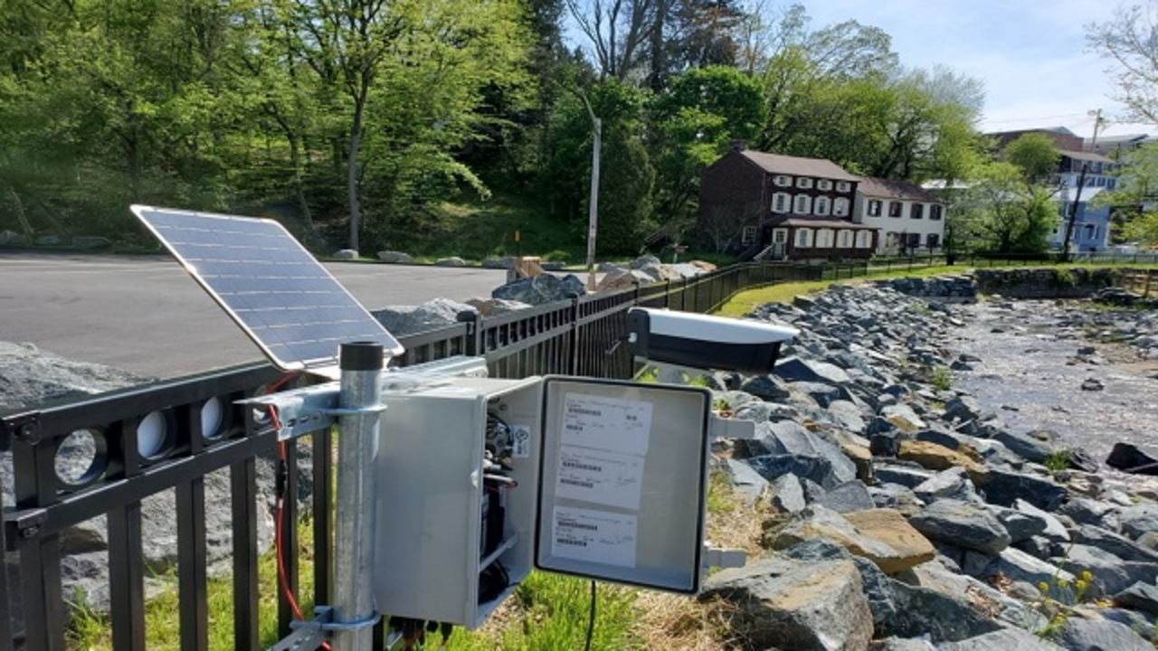 solar powered machine box attached to a bridge near a stream of water