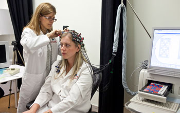 a young woman being prepared by a researcher for a brain imaging system.