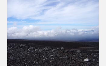 Photo of the twisting road, Mauna Loa's lava fields and clouds.