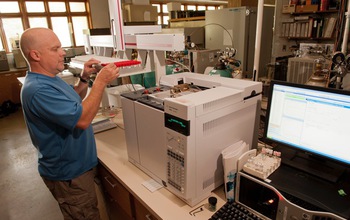 LTER scientist Kevin Kahmark next to equipment analyzing samples in the lab.