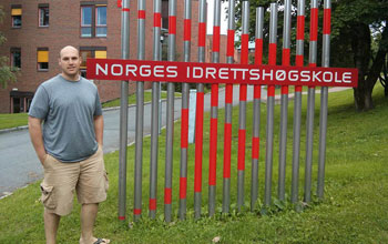 GROW student Erich Petushek standing next to a sign at the Norwegian School of Sports Sciences