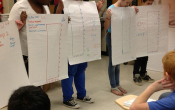 Middle school students holding sheets during a presentation