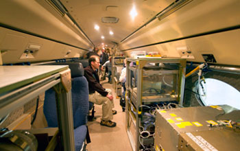 Photo of atmospheric scientists loading air-sampling instruments into HIAPER.