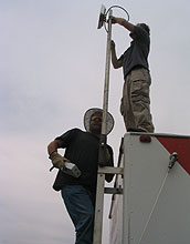 Two men work on a communications antenna.