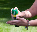 person spraying insect repellant on hands