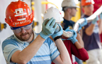 Photo of curator Chad Broyles leading technicians carrying a core from the ship's drill floor.