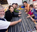 Photo of members of the expedition science party looking at a core sample in a shipboard lab.