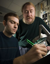 Photo of Richard Lenski and another researcher examining a Petri dish used in a study of evolution.