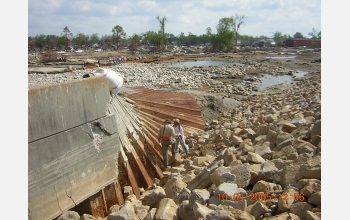 Researchers inspect a portion of the floodwall that was overtopped and flattened.