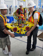 Photo of three Long Beach City College ROV Team members transporting their vehicle from the pool.