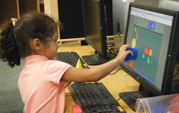 Photo of a girl using a computer to match shapes to build pictures.