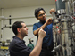 Photo of Ben Levinson watching Rama Balasubramanian adjust the levels of gases in a fermenter.