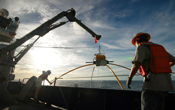 Marine scientists on a ship at sea hauling in an electromagnetic receiver.