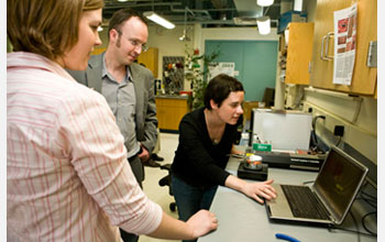 Photo of Charles Sykes and graduate students looking at images of molecules on a computer screen.