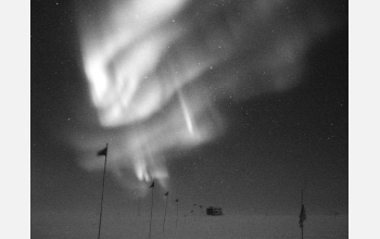 <em>Aurora Australis</em> over flagline to a building in clean-air sector of Amundsen-Scott