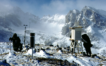 researchers checking instruments on top of a mountain