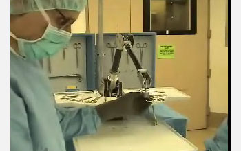 Screen capture from video showing surgeon and robot in an operating room