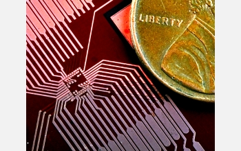 A device pad structure is shown next to a penny for comparative size