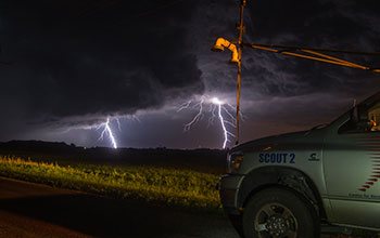 Cloud-to-ground lightning and PECAN vehicle during nighttime thunderstorm