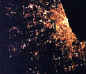 Photo showing bright lights of Chicago on the right fading into dark rural landscapes on the left.