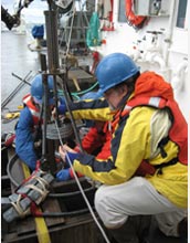 Photo of WHOI scientist Bruce Keafer, right, preparing a corer to collect seafloor sediment samples.