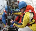 Photo of WHOI scientist Bruce Keafer, right, preparing a corer to collect seafloor sediment samples.