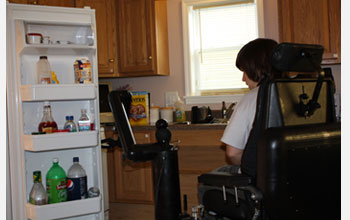 Photo of person with disabilities piloting a robotic mobility and manipulation system in kitchen.