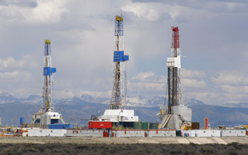 Photo of three natural gas drilling rigs.